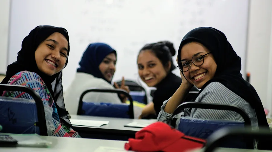 Students at a Chegu Khairi class, with the worked solutions still on the whiteboard behind them